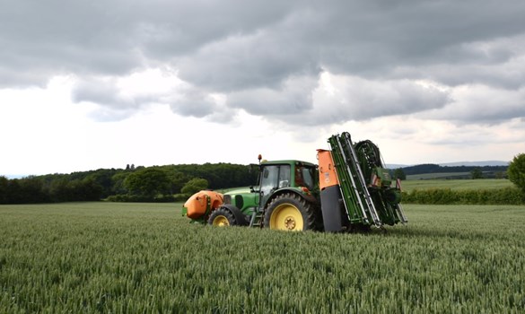 Tractor with spraying equipment in a field of crops